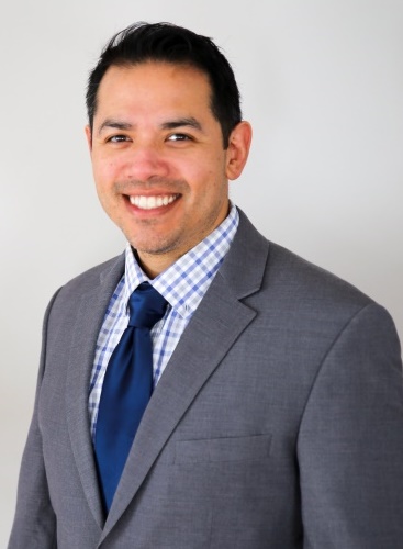 Man wearing a gray suite and Blue tie.